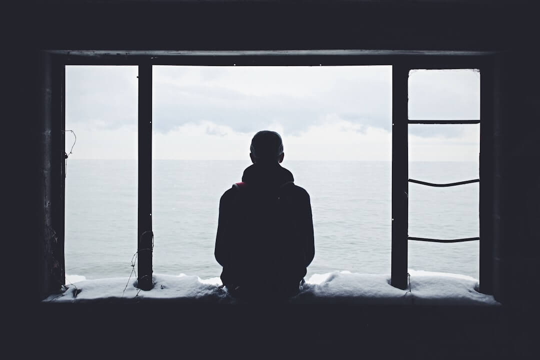 A person sitting alone on a couch looking at their phone late at night, waiting for a text